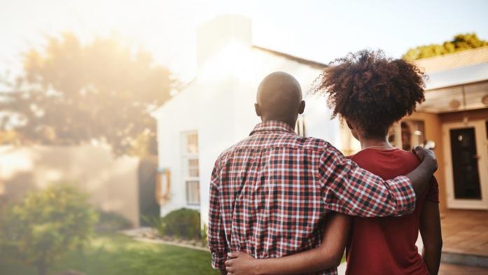 couple arm in arm looking at a house