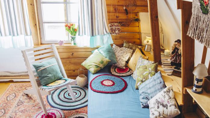 Maximalist maximalist home concept. Holiday home cabin bedroom with natural wooden board walls and ceiling and lot of different color details.