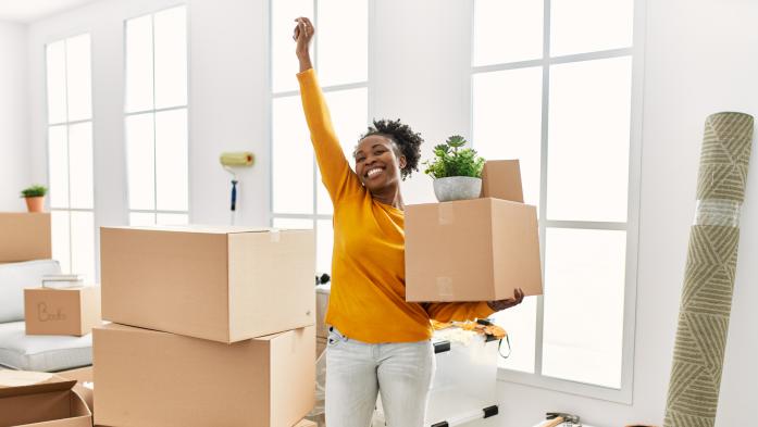smiling woman unpacking boxes, happy with one arm raised in victory