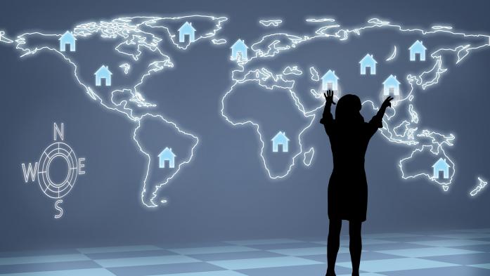 woman standing in front of digital world map with house logos