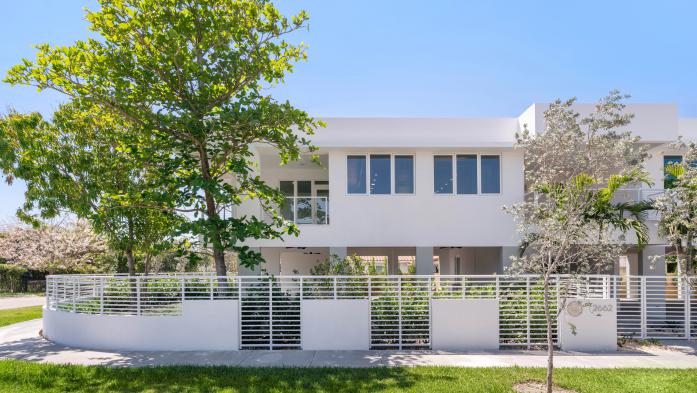 image of healthy sustainable home built in florida. white block-shaped home with trees in front 