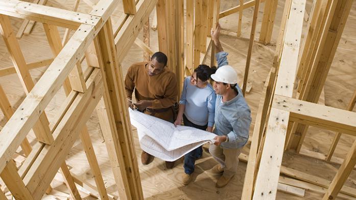 photo from above of a couple looking at blueprints in a new home