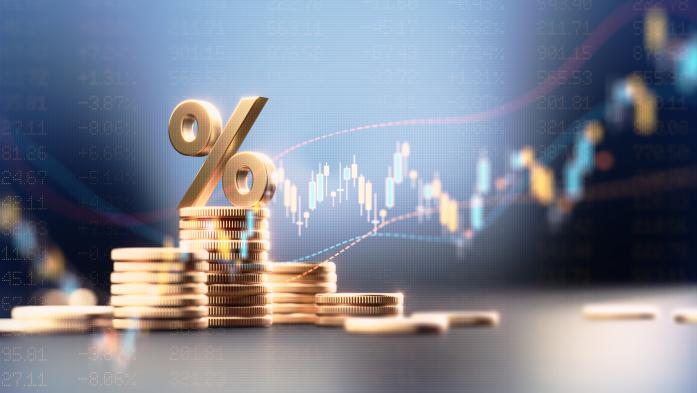Percentage sign on top of coin stacks before blue financial graph. Horizontal composition with copy space. Business and finance concept.