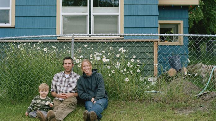 couple and child sitting in front of a chain link fence 