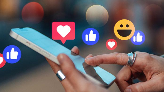 photo illustration of hands holding a phone with like emojis floating above