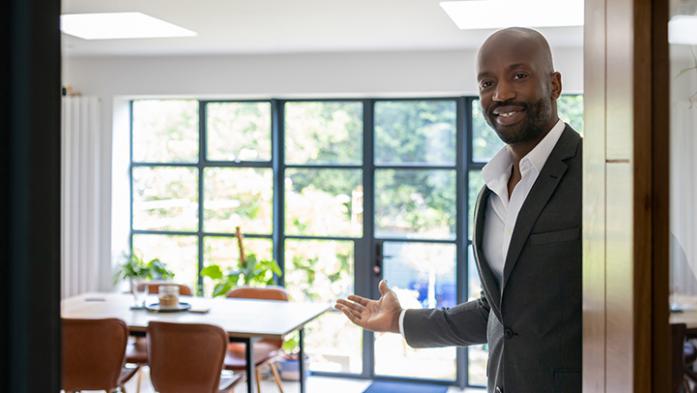 Photo of a black, male real estate agent opening a front door