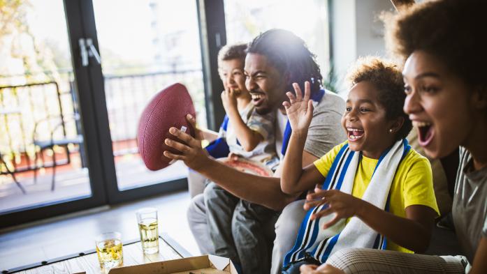 Happy family watching football on TV and eating pizza 
