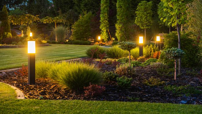 Modern Backyard Outdoor LED Lighting Systems - stock photo  Panoramic Photo of LED Light Posts Illuminated Backyard Garden During Night Hours. Modern Backyard Outdoor Lighting Systems.