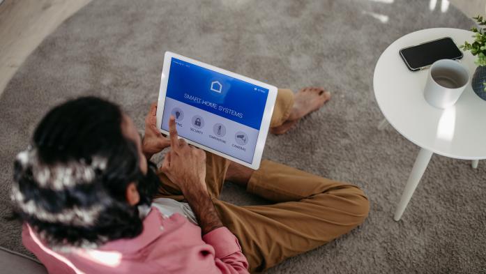 Man adjusting household functions, lighting, security cameras, door locks and thermostat or heating settings in the smart home system. - stock photo