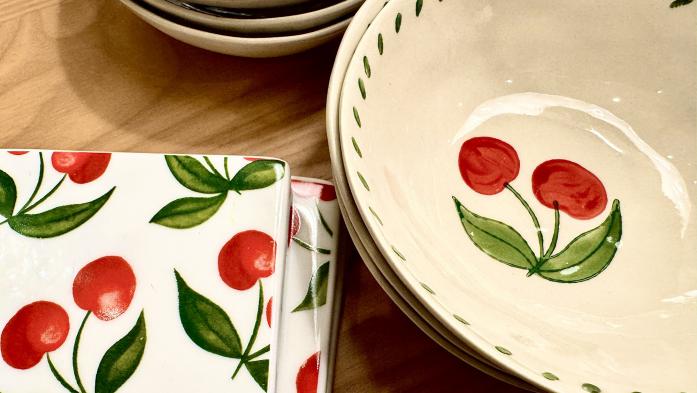 Food bowls and coasters with a cherry theme on a wooden table -