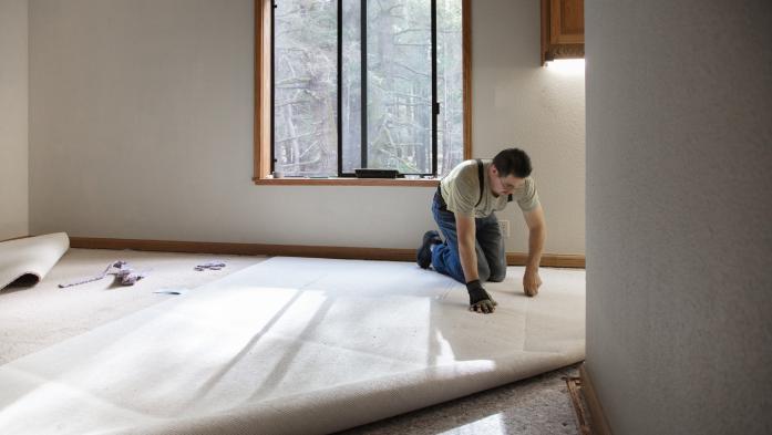 Man installing carpeting in home.