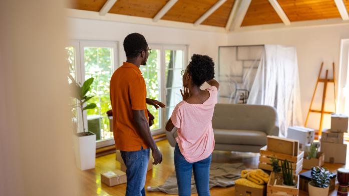 Two people, happy young black couple standing in their new apartment.