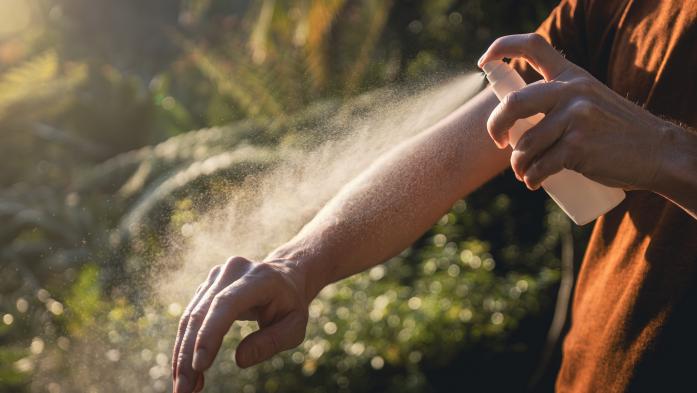 Man while applying insect repellent on his arm. Prevention against mosquito bite in tropical destination