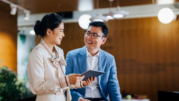 Asian business partners working on a digital tablet and laptop computer in the office. 