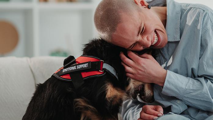image of a young person hugging emotional support dog on a couch