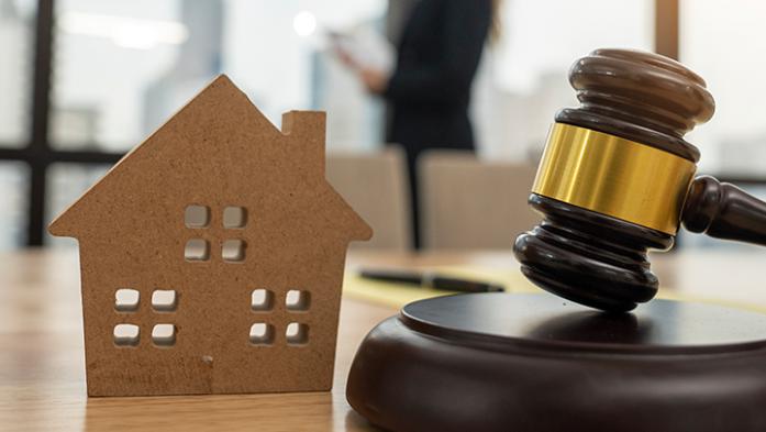 Photo of gavel and wooden house on a desk