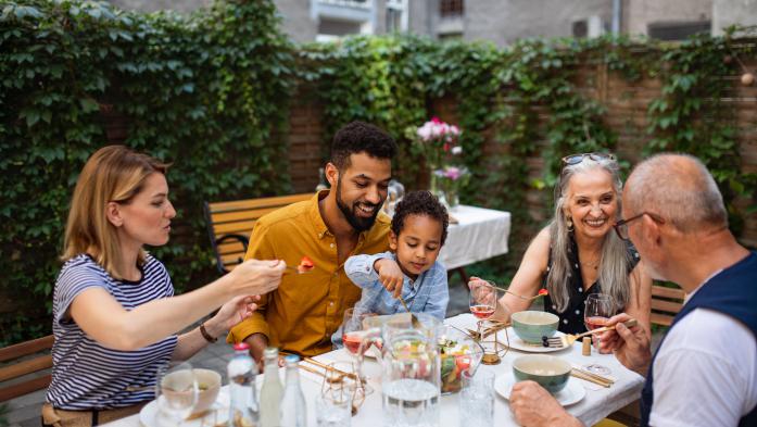 ortrait of multiracial three generations family having dinner together outdoors in front or back yard.
