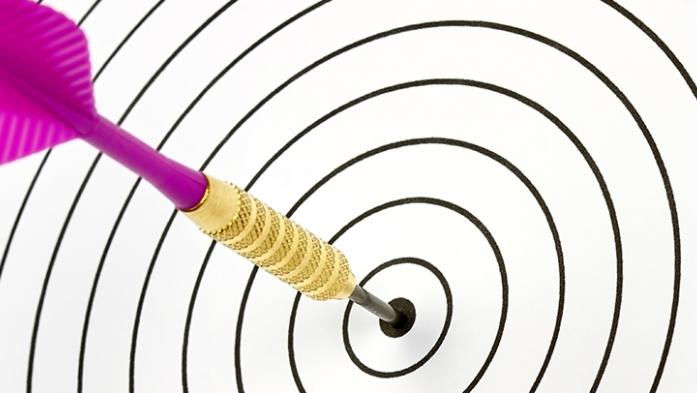 Photo of a dartboard with a pink dark hitting the center