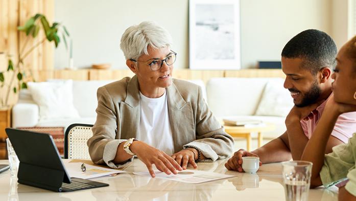 Photo of real estate agent talking to clients at dining room table