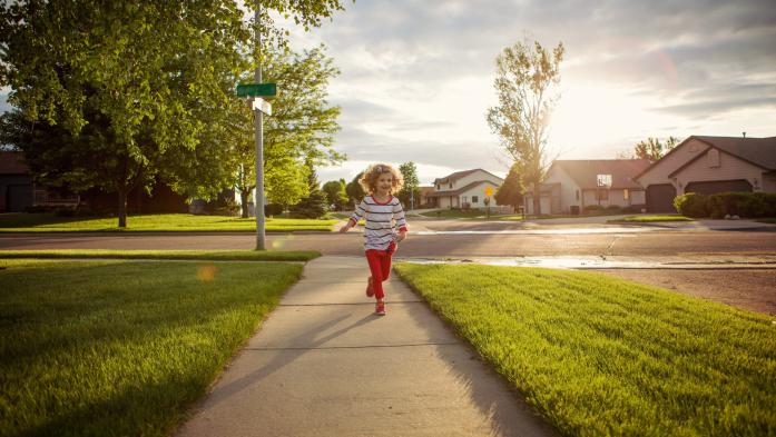 child playing on sidewalk in neighborhood