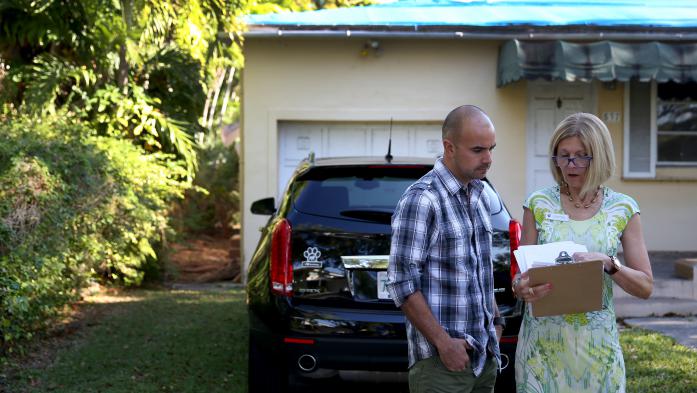 Realtor reviewing paperwork with a client outside a home