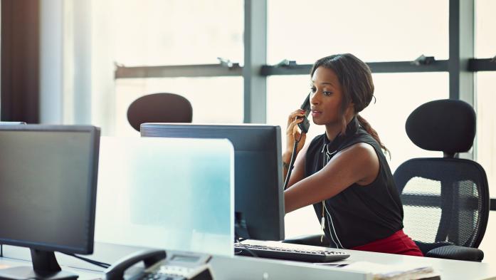 woman at computer using telephone