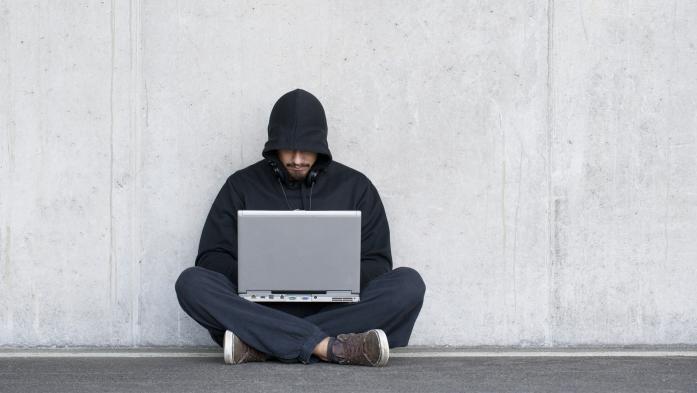 man in hood using computer