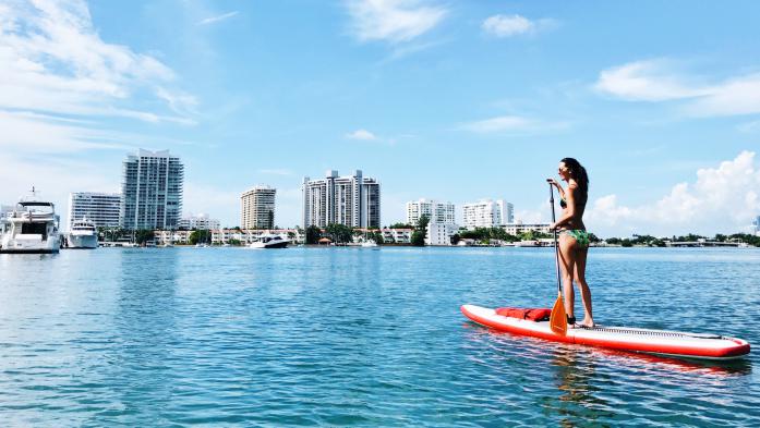 woman paddleboarding with florida skyline in background