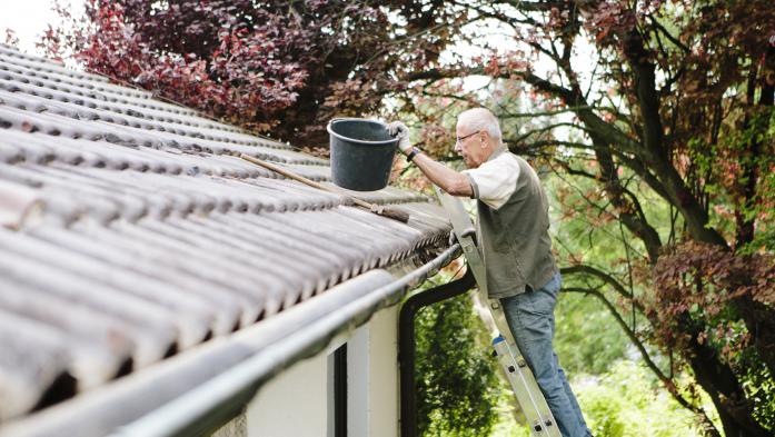 man on ladder cleaning gutters