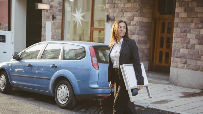 realtor with sign crossing street