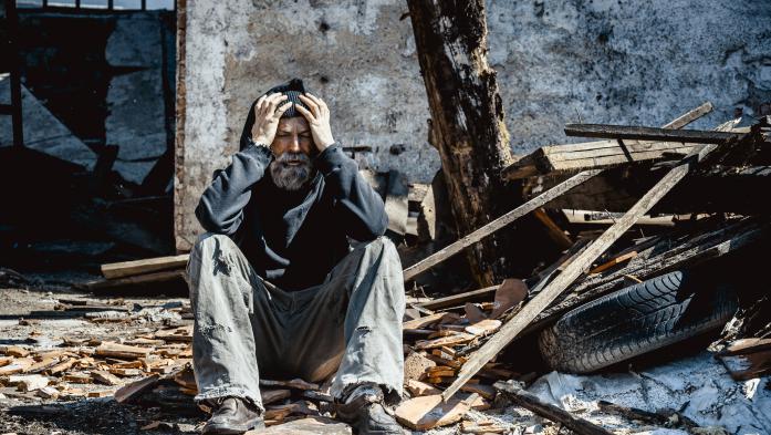 distraught man sitting in rubble