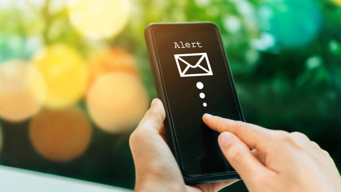 Hands holding phone with email alert on screen