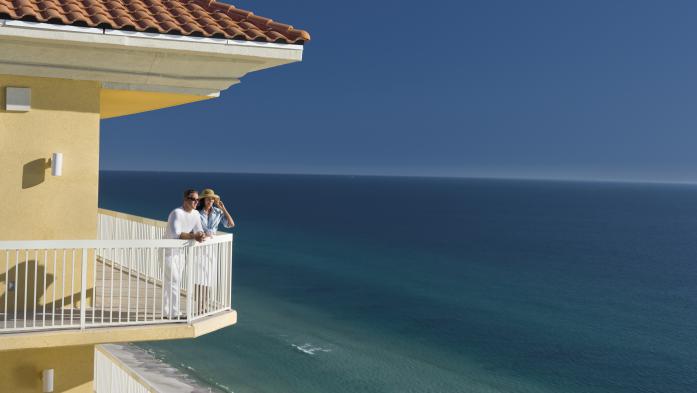 Couple stands on balcony overlooking the ocean