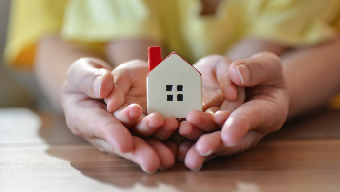 And adult and child's hands holding tiny house