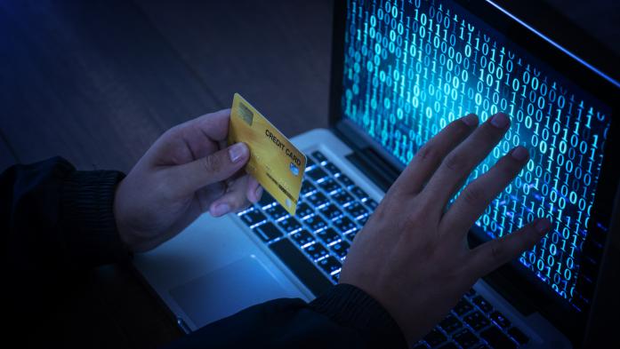 Hand with a credit card hovering in front of a computer screen