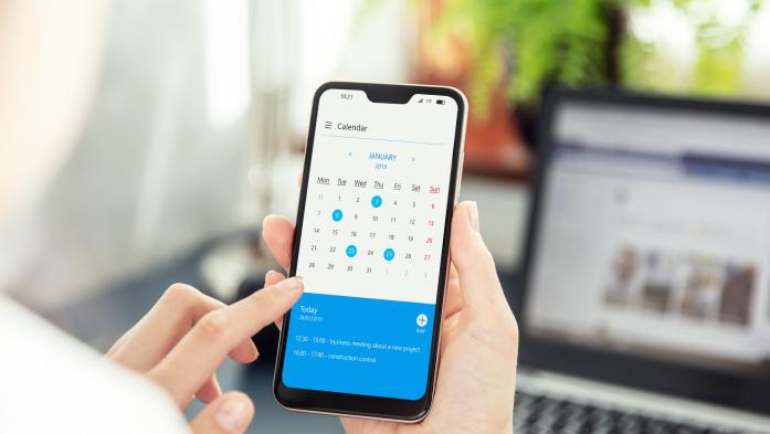 Hands holding phone looking at calendar