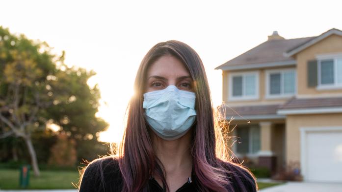 woman wearing face mask outside a house