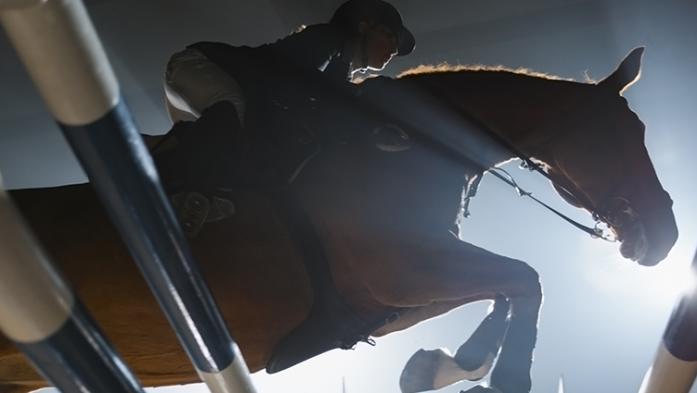 equestrian rider jumping over an obstacle