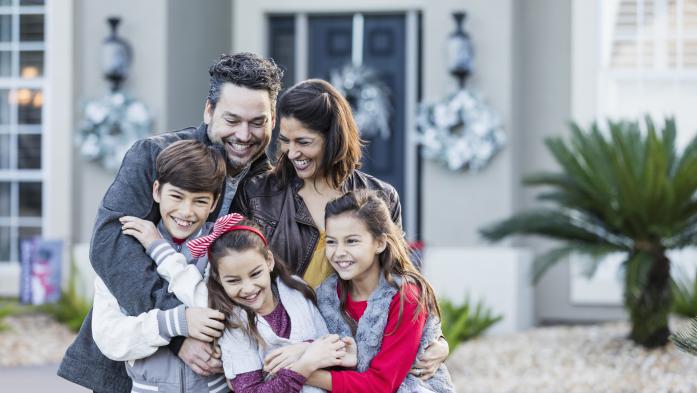Happy family of five in front of new home
