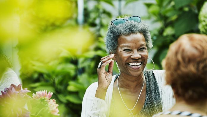 Older woman smiling while outdoors talking to another woman