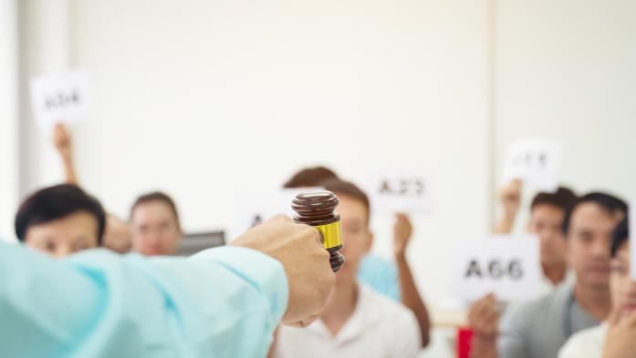 Bidders face a hand with a gavel during auction