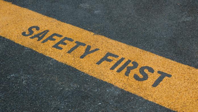 image of road asphalt with yellow line across it saying safety first