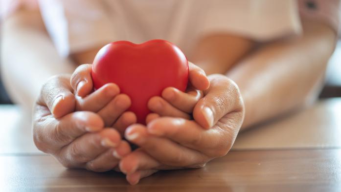 Heart held by a child's hands that are held by an adult's hands