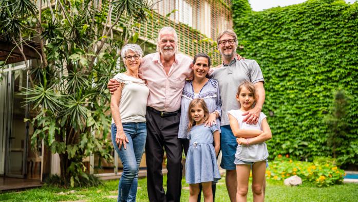 Five people from three generations tand in front of a house