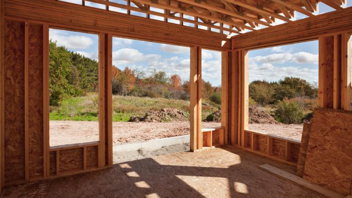 Partially constructed room with large windows and doors facing greenspace