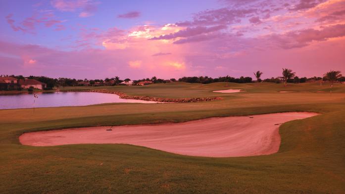 Golf course in red light of sunset with homes in the background