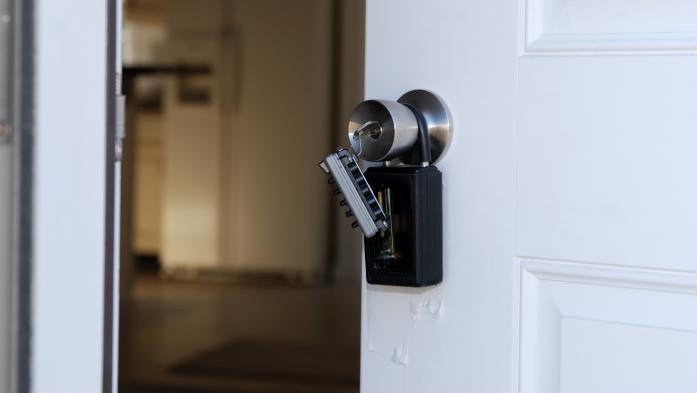 White door stands ajar with a lockbox over the outside knob