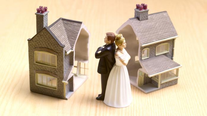 Cake topper couple back to back with two toy homes in background