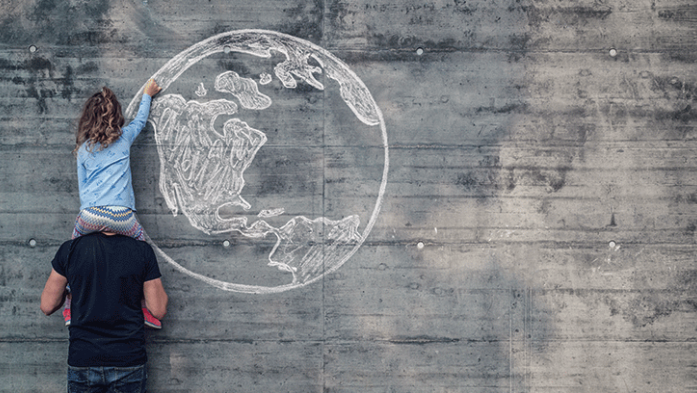 hoto of child drawing a globe in chalk on a grey wall