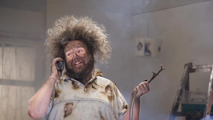 Home remodeler with blackened face and electrical wiring in one hand